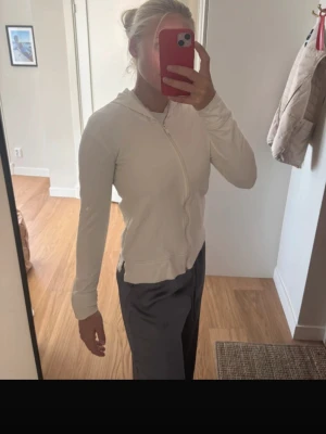Vit tröja med dragkedja - Säljer en enkel och stilren vit hoodie med dragkedja och huva. Hoodien har långa ärmar och är gjord i ett mjukt material som passar perfekt för en avslappnad look. Passar dig som gillar basic och clean stil. Lik en define jacka. 
