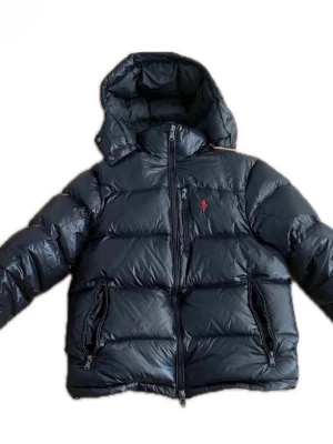  Ralph Lauren jacka  - Svart pufferjacka från Ralph Lauren med huva och dragkedja framtill. Jackan är äkta och väldigt varm och skön! Meddela mig gärna om ni har några frågor! 