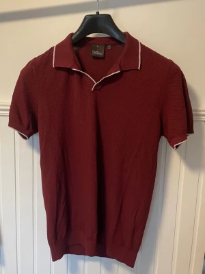 Oscar Jacobson stickad piké vin röd - Väldigt snygg stickad piké av Oscar Jacobson i en limiterad vin röd färg. Pris kan diskuteras vid snabb affär.