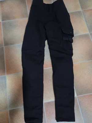 Helt nya MC-leggings från KRS - Strl S/26 - Snygga och skyddande cargo-leggings i nyskick med alla märkeslappar kvar! Perfekta för dig som vill ha stil och säkerhet på hojen.  • Säkerhet: Heltäckande Kevlar-foder för max slitstyrka & CE-godkända skydd för knä/höft ingår.  • Funktion: Vattentäta & stretchiga med hög midja för grym komfort.  Detaljer: Praktiska cargo-fickor & robust textil.  Nypris: 1 499 kr. Oanvända i originalförpackning!