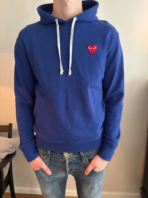 Blå hoodie från Comme des Garçons - Säljer nu en blå hoodie från Comme des Garçons Play med vita snören och det klassiska röda hjärtat. Storleken är M, Säljer hoodie för endast 499kr! Skriv om du har några funderingar om plagget.