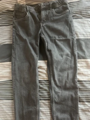 Grå slim fit jeans - Snygga grå slim fit jeans med klassisk femficksdesign och normal midja. Jeansen har en stilren look och passar perfekt till en avslappnad streetstyle. Materialet är mjukt och stretchigt för extra komfort.