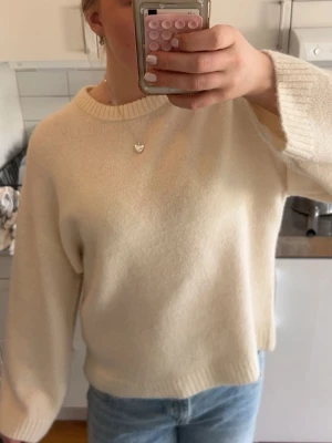 Krämvit stickad tröja Gina Tricot - Mysig krämvit stickad tröja från Gina Tricot med rund halsringning och avslappnad passform. Tröjan har ribbade muddar vid ärmslut och nederkant, perfekt för lager på lager och enkel att styla till jeans eller kjol. Materialet är mjukt.