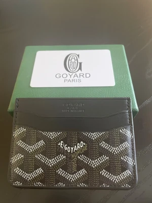 Svart kortfodral från Go4yard  - Snyggt och stilrent kortfodral från Go4yard i svart med det klassiska Go4yard-mönstret i vitt och grått. Fodralet har flera kortfack och är tillverkat i canvas och läder. Perfekt för dig som vill ha en exklusiv accessoar med Paris-vibe.
