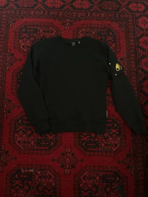 Svart Moose Knuckles tröja - Svart sweatshirt från Moose Knuckles med rund hals och lång ärm. Fint skick utan defekter har använts förra året passar även XS 