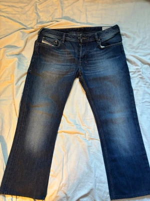 Diesel Zatiny Bootcut – Mörkblå (W33/34)  - Säljer ett par superfina Diesel Zatiny i en klassisk mörkblå tvätt (Wash 008J4). Modellen är en tidlös bootcut med perfekt passform över låren och snygg utsvängning nertill.Passformen på dessa Zatiny liknar Levi's vintage modeller 527 och 512 men med Diesels välkända kvalitet och snygga detaljer.  Viktig info om storleken: Lappen säger W33 L34, men de är professionellt uppsydda. • Midjemått: ca 44-45 cm platt • Innersöm (längd): ca 66  cm 