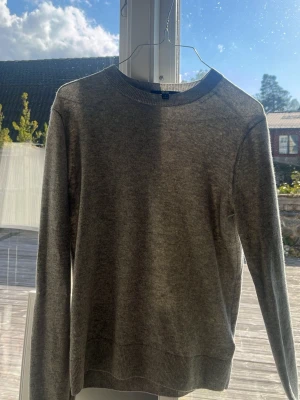 Grå cashmere-tröja med rund hals - Mjuk och stilren grå stickad tröja i 100% cashmere med rund halsringning och långa ärmar. Perfekt för lager-på-lager och enkel att matcha med olika outfits. Ribbstickade muddar vid ärmslut och nederkant ger en snygg finish.