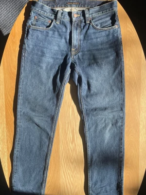 Nudie Jeans. Modell: Gritty Jackson - Säljer ett par Nudie Jeans i modellen Gritty Jackson, colorwayen Blue Soil. En liten del från sömmen på höger ficka har försvunnit lite, men det påverkar inte plagget. 