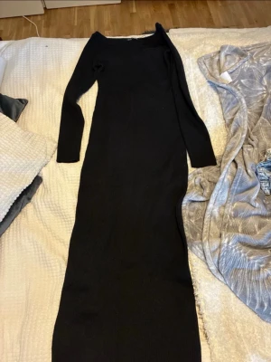 Svart långärmad klänning från Zara - Snygg svart långklänning från Zara med lång ärm och rund halsringning. Klänningen är ribbad och har en tight passform som framhäver siluetten. Perfekt för dig som gillar stilrena och minimalistiska looks.