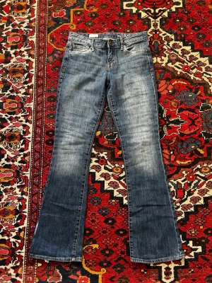 Blå bootcut jeans med tryck på bakfickorna - Jag säljer ett par coola blå jeans med lite ljusare inslag, dem har samt märken på bakfickorna. Jeansen är något små på mig och kommer därför sitta mer boutcut på nån med rätt storlek🤗 Jeansen passar någon mellan storlek xs-s