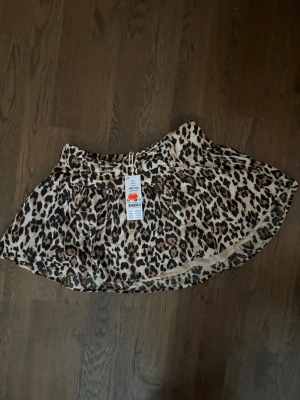 Leopardmönstrad kortkjol - Kort volang kjol i leopard mönster i storlek 146/152 (barnstorlek) men skulle säga att det passar som storlek Xs/S också. Helt oanvänd med prislapp kvar från Gina Tricot.