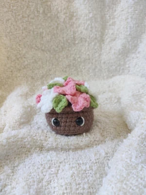 Virkad blomkruka  - Virkad blomkruka med rosa och vita blommor. Cirka 7 cm bred och 7 cm hög. Har tre likadana, därav tre annonser. 