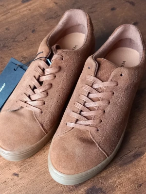 Bruna mockasneakers från Vero Moda - Snygga bruna sneakers i mocka från Vero Moda med klassisk låg profil och matchande bruna skosnören. Yttersulan är i gummi och skon har en stilren, minimalistisk design som passar till det mesta. Perfekta för dig som gillar en clean och trendig look.