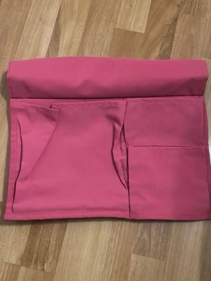 Rosa organiseringsväska i tyg - Praktisk rosa organiseringsväska i tyg med flera fack, perfekt för att hålla ordning på småsaker som pennor, smink eller tillbehör. Enkel och stilren design med mjukt material och vikbar öppning.