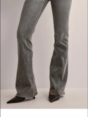 Grå bootcut jeans med utsvängda ben - Snygga grå bootcut jeans med utsvängda ben och klassisk femficksdesign. Jeansen har en tvättad look och normal midja. Perfekta för dig som vill ha en trendig och avslappnad stil. Lite slitna längst ner men inget jätte synligt 