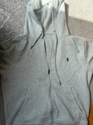 ~ Ralph lauren - zip hoodie ~ - Stilren Ralph lauren zip hoodie tröja i grå, perfekt till sommarn. Tröjan är även aldrig använd.                                                                       Storlek är S - men passar som en m i storlek. Hör av er om ni är sugna och tveka inte på att ge prisförslag!🚨🚨🚨