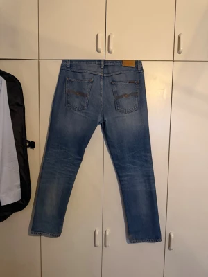 Nudie Jeans gritty jacksson - Säljer ett par klassiska blå jeans från Nudie Jeans med rak passform. Modell gritty jacksson. Slitningar se bild 