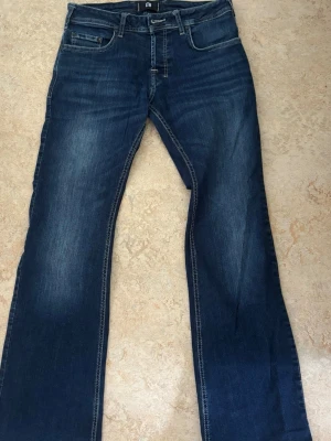 Mörkblå bootcut jeans från LTB - Snygga mörkblå bootcut jeans från LTB med klassisk femficksmodell och slitningar framtill. Jeansen har normal midja och är tillverkade i denim med lätt stretch för skön passform. Perfekta för en avslappnad och trendig look.   29/30