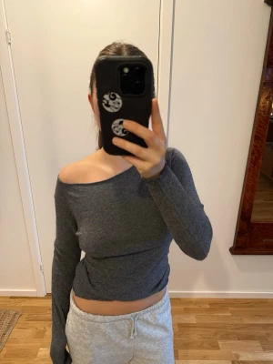 Grå off shoulder tröja i kaschmir - Snygg grå off shoulder tröja med lång ärm och tight passform i kaschmirblandning! Köpt i Rom, Italien. 