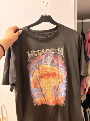 Svart Megadeth t-shirt från Istay - Cool svart t-shirt från Istay med Megadeth-tryck framtill i färgstarka toner. Klassisk rund hals och korta ärmar. Perfekt för dig som gillar bandtröjor och vill sticka ut med en unik print. Materialet känns mjukt och skönt mot huden.