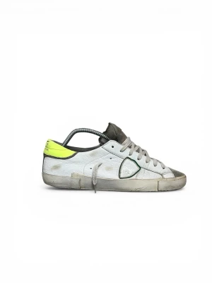 Philippe Model vita sneakers med neon - Snygga vita Philippe Model sneakers med detaljer i neon-gult på hälen och grått på tån. Skorna har en låg siluett, vita snören och den klassiska sköldloggan på sidan. Materialet är läder med slitna detaljer för en cool, avslappnad look.