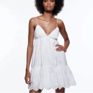 Vit Zara klänning - Söt vit klänning med tunna axelband och v-ringning. Klänningen har broderade hålmönster och volangkant nertill. Lätt och luftig modell, perfekt för varma dagar. Kort längd och avslappnad passform. Kontakta mig för frågor och fler bilder❤️