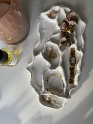 Vit vågig smyckesbricka - Handgjord smyckesbricka i lufttorkad lera med vågig, organisk form. Perfekt för att förvara ringar, armband, klocka och andra små accessoarer på nattduksbordet eller sminkbordet. Ger en stilren och modern känsla till rummet.