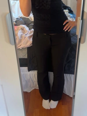 Svarta kostymbyxor med raka ben - Snygga svarta kostymbyxor med raka ben och klassisk passform. Byxorna har hällor för skärp, diskreta sidofickor och stängs med knapp och dragkedja. Perfekta för en stilren look och passar till många olika outfits. Säljer pga nån liten cm för kort! Jag är 163🥰 använda 1 gång 