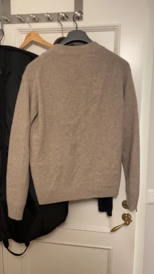 Beige kofta uniqlo  - Stilren beige kofta med v-ringning och tre knappar framtill. Koftan har två praktiska fickor och ribbade muddar vid ärmslut och nederkant. Perfekt att slänga över en t-shirt för en avslappnad look. Pris är diskuterbart. Den är i merinoull eller cashmere 