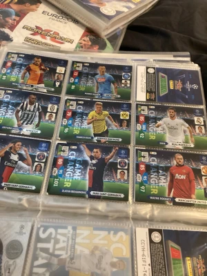 Samling fotbollskort Champions League game changer” 2013/2014 - Säljer en samling fotbollskort från Champions League med spelare som Zlatan Ibrahimovic, Wayne Rooney och Marco Reus. Korten har färgstarka designer, klubbmärken och spelarstatistik. Perfekt för dig som gillar att samla på fotbollsprylar eller vill byta med vänner.