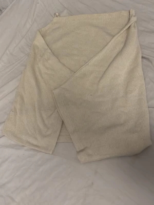 Beige poncho  - Mysig beige poncho i mjukt frottématerial. Enkel omlottmodell med knytband i midjan och klassisk design. Perfekt för att slappa hemma eller efter duschen.