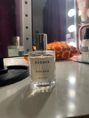 ESSNCE Rose Rose Eau de Parfum - Fräsch parfym från ESSNCE med doft av rosor. Flaskan är genomskinlig med en stilren, cylindrisk form och har ett silverfärgat lock. Minimalistisk etikett med svart text. Perfekt för dig som gillar blommiga dofter och enkel design.