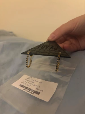 LUV AJ Ballier Chain örhängen guld/blå - Snygga örhängen från LUV AJ i modellen Ballier Chain Studs. De är guldfärgade med blå safirliknande stenar längs hela kedjan. Helt oanvänd 