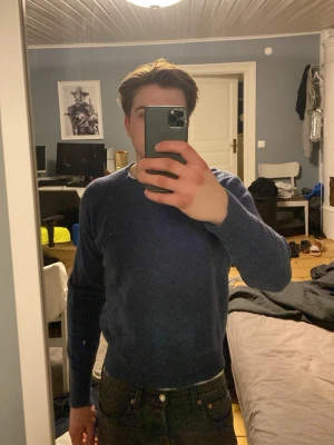 Mörkblå rundhalsad tröja - En stilren mörkblå tröja med rund halsringning och långa ärmar. Tröjan har en enkel, klassisk design och är tillverkad i ett mjukt material som passar perfekt till jeans eller chinos.