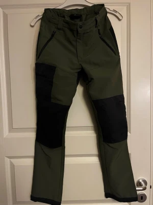 Gröna outdoorbyxor Everest stl 158 - Säljer ett par gröna outdoorbyxor med svarta förstärkningar på knän och bak. Byxorna har dragkedjeförsedda fickor framtil och vid höger ben. Justerbar midja. Perfekta för outdoor-aktiviteter. Materialet är slitstarkt och stretchigt. Stl 158