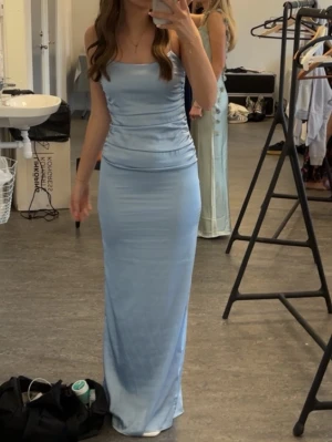 Ljusblå långklänning med öppen rygg - Säljer just nu min balklänning som inte kommer till användning längre. Andvänd ca 3 gånger och den är väl omhändertagen. Elegant ljusblå långklänning med smala axelband och figurnära passform. Klänningen har en stilren, rak siluett och öppen rygg, vilket ger en modern och sofistikerad look. Perfekt för speciella tillfällen när du vill sticka ut. Storlek 34 men borde passa 36 också då jag oftast har de.