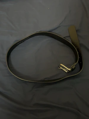 Svart skärp från Jack & Jones - Snyggt svart bälte från Jack & Jones i klassisk design. Tillverkat i skinn med en enkel metallspänne. Perfekt för att lyfta vilken outfit som helst och funkar till både jeans och kostymbyxor.