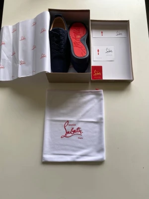 Marinblå sneakers från Christian Louboutin - Snygga marinblå sneakers från Christian Louboutin med klassisk röd sula och broderad logga på hälen. Kommer med originalkartong och dustbag. Perfekta för dig som vill sticka ut med exklusiv stil. Helt nya!! Priset är diskuterbart,st 43 😃👍