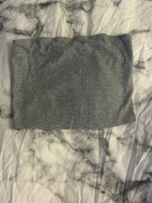 Grå ribbad tubtopp - Snygg grå ribbad tubtopp som sitter tight och är perfekt till sommaren. Enkel att matcha med både jeans och kjol för en trendig look. Mjuk och stretchig, passar dig som gillar minimalistisk stil.
