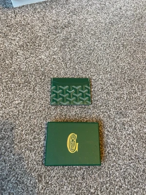 Grönt korthållare med mönster - Snygg grön korthållare med mönstret i vitt och grönt. Tillverkad i canvas och läder, perfekt för kort och ID. Kommer med originalask i matchande grön färg och gulddetaljer.