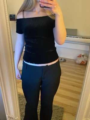 Svart offshoulder topp med smock - Svart offshoulder topp. Toppen är axelbandslös och har en croppad längd som ger en snygg siluett. Använd ungefär 3 gånger så ser ut som ny. Jag på bilden är ca 163 cm