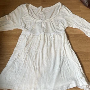 Vit blus från American Eagle - Supersöt vit blus från American Eagle med långa ärmar , knappar framtill och broderad logga nertill. Blusen har fina spetsdetaljer längs kanterna. Skriv för frågor💗