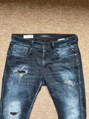 Mörkblåa replay jeans - Säljer ett par mörkblå jeans från Replay med slitningar och trasiga detaljer på benen. Jeansen har fem fickor, knappgylf och klassisk slim passform. Översnygg och unik tvätt, dessa jeans är riktigt svåra att få tag på. Som vanligt är priset diskuterbart mina vänner❤️🚀