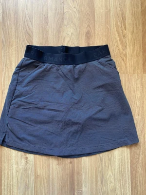 Svart tenniskjol från Peak Performance - Sportig svart tenniskjol från Peak Performance med bred resår i midjan där loggan är diskret invävd. Kjolenhar en lätt A-linjeform och är tillverkad i ett stretchigt funktionsmaterial som passar perfekt för en aktiv livsstil.