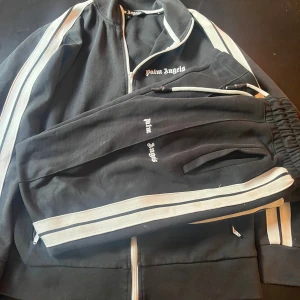 Palm Angels Tracksuit  - En svartvit Palm Angels tracksuit i strl M. Den är i gott skick men har några små defekter, men de märks inte av vid användning. 