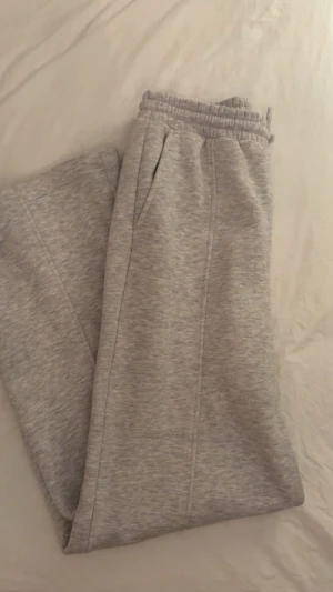 Grå mjukisbyxor med resårmidja - Säljer ett par ljusgrå mjukisbyxor med resår i midjan och raka ben. Byxorna har sidofickor och är gjorda i mjukt sweatshirtmaterial, perfekta för chill dagar. Klassisk och enkel design som passar till det mesta.