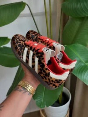 Adidas sneakers med leopardmönster - Unika Adidas sneakers med leopardmönstrad ovandel, klassiska vita ränder på sidorna och brun sula. Skorna har röda detaljer vid öppningen och vita skosnören. Perfekt för dig som vill sticka ut med en djärv och trendig stil.