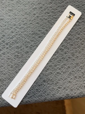 Guld och silver tennisarmband - Snyggt armband med två rader gnistrande stenar i guld och silverstenar. Armbandet har en klassisk och stilren design med små pärlliknande detaljer som ger extra bling. Perfekt accessoar för att lyfta din outfit.