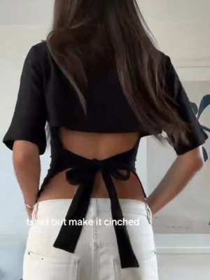 Svart croppad topp med knyt i ryggen - Svart croppad topp med kort ärm och snygg knytning i ryggen. Enkel och stilren design som passar perfekt till jeans eller kjol. Mjuk och skön känsla, troligtvis i bomull eller polyester. Perfekt för dig som gillar minimalistisk stil. Se sista bilderna för lagning💗