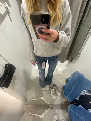Blå Gina Tricot jeans - Säljer ett par blå Gina jeans med slitningar och hål på benen. Storlek 158 och har fina detaljer på bakfickorna.
